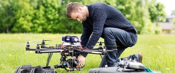 Young engineer setting SLR camera on UAV helicopter at park